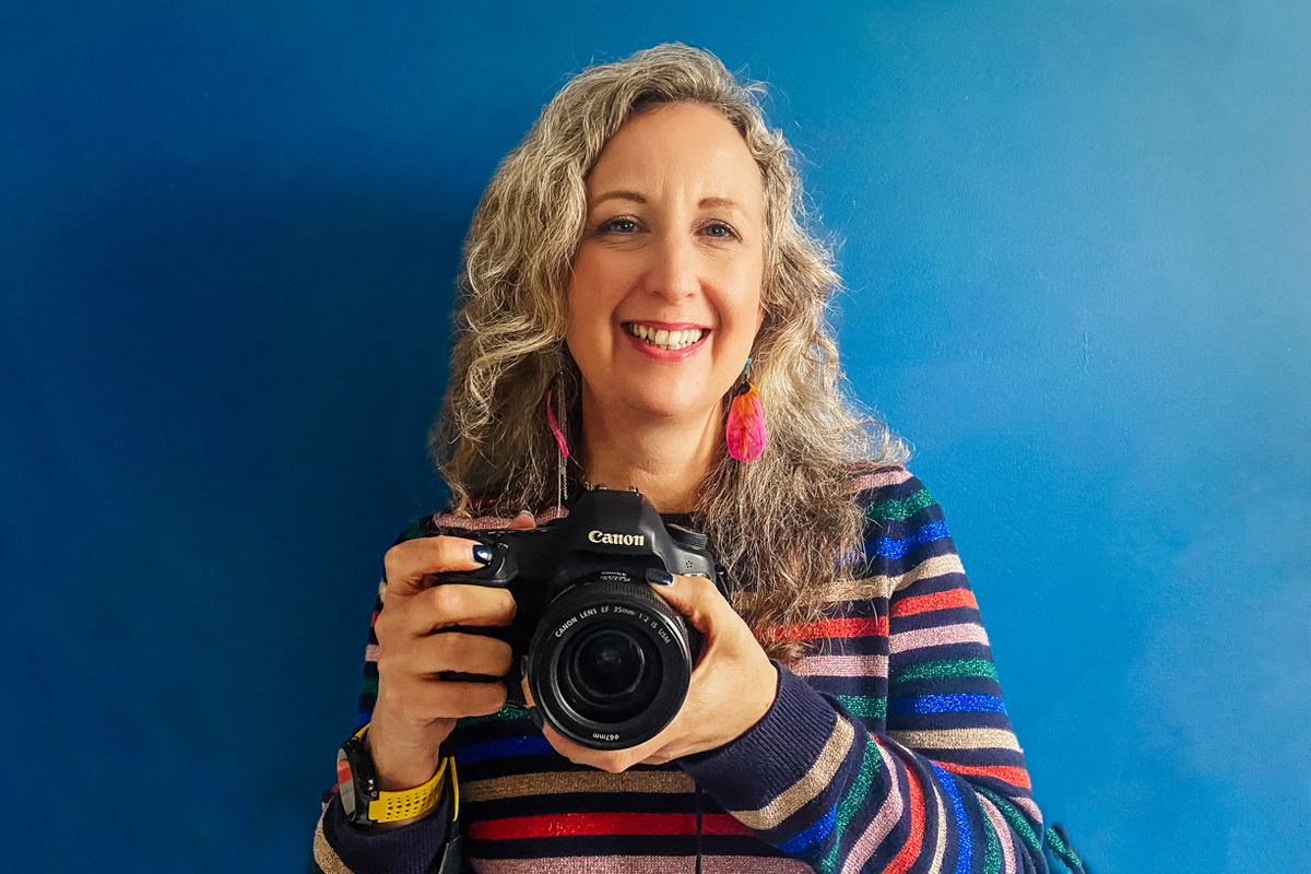 Becky Craven with camera on blue wall